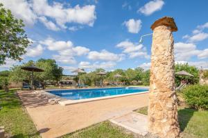a swimming pool in a yard with a stone pillar at Finca Son Marimon in Santanyi