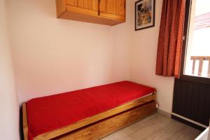a small room with a red bed in the corner at Résidence Grande Ourse - 2 Pièces pour 4 Personnes 40 in Peisey-Nancroix