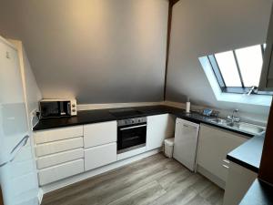 Elle comprend une petite cuisine avec des placards blancs et une fenêtre. dans l'établissement Glastonbury Secret Retreat - 1 BD Split-Level Apt, Sleeps 3, à Glastonbury 19 autres photos