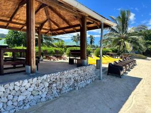 uma parede de pedra com cadeiras e um pavilhão em Maison Te Manu - plage privée avec vue sur Tahiti à quelques pas em Maatea