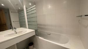 Résidence Le Cristal - 2 Pièces pour 4 Personnes 34 في Les Allues: حمام أبيض مع حوض وحوض استحمام