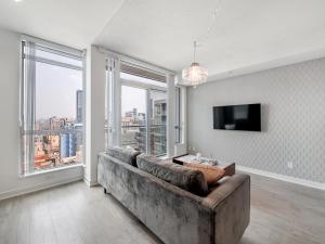 Designer One Bedroom Suite - Entertainment District Toronto في تورونتو: غرفة معيشة مع أريكة ونافذة كبيرة