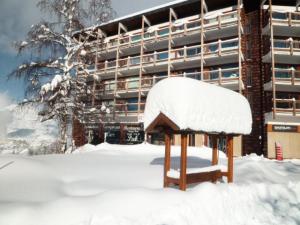 un banc recouvert de neige devant un bâtiment dans l'établissement Résidence Les Charmettes - Studio pour 3 Personnes 51, à Arc 1600