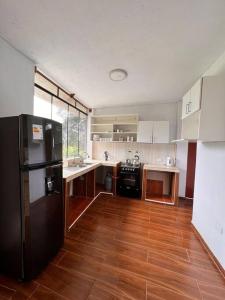 uma cozinha com um frigorífico preto e piso em madeira em Casa de Campo Oro Verde San Jose em Oxapampa