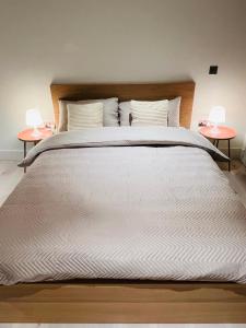 a large bed with white sheets and two tables at Private Room@LeicesterSquare in a Shared Flat in London