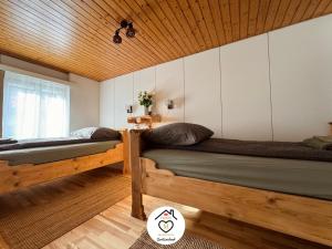 two beds in a room with a wooden ceiling at Family M Apartments 6 in Sempach
