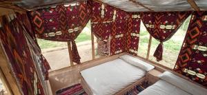 małe łóżko w pokoju z zasłonami i oknem w obiekcie siwa gardenia cottage w mieście Siwa