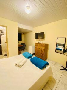 a bedroom with a bed with blue pillows and a television at Hospedaria Vila Rica in Ouro Preto