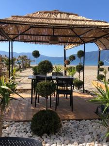 - une table et des chaises sous un pavillon sur la plage dans l'établissement Soleil Apartment with sunbed & umbrella, à Vlorë