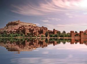 un castillo en una colina junto a un cuerpo de agua en WARZAZAT Hostel, en Ouarzazate