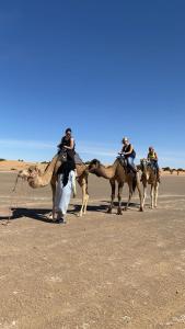 メルズーガにあるMerzouga Luxury Campsの砂漠のラクダに乗る人々