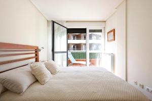 1 Schlafzimmer mit einem weißen Bett und einem Balkon in der Unterkunft Playa, río y monte en 1ª linea in Orio