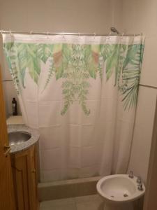 y baño con cortina de ducha y lavamanos. en departamento equipado Pioneros en Zapala