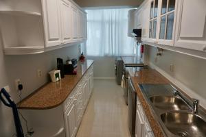 a kitchen with white cabinets and a sink at Alma Beach House in Costa da Caparica