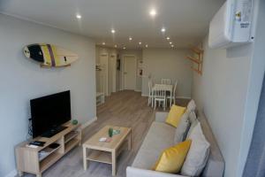 a living room with a couch and a flat screen tv at Alma Beach House in Costa da Caparica