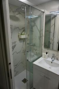 a bathroom with a glass shower and a sink at Alma Beach House in Costa da Caparica