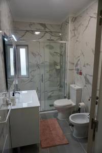 a bathroom with a shower and a toilet and a sink at Alma Beach House in Costa da Caparica