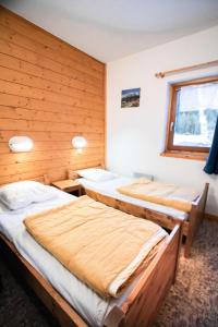 3 camas num quarto com paredes de madeira e uma janela em Résidence Les Portes De La Vanoise - 2 Pièces pour 6 Personnes 193054 em Villarodin-Bourget