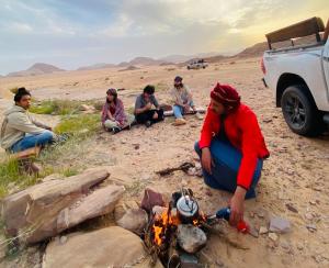 a group of people sitting around a campfire at Wadi Rum Jordan Camp in Wadi Rum