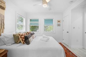 a white bedroom with a large white bed with windows at 29 Palms in Anna Maria
