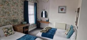 a bedroom with two beds and a desk and a mirror at Hawthorn House in Blackpool