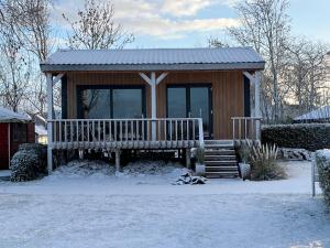 a small cabin with a bench in the snow at Camping Kleine Belterwijde, Wiede Lodge met uitzicht over het water in Belt-Schutsloot