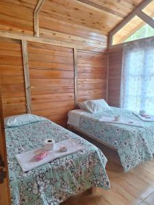 two beds in a room with wooden walls at Oxaturismo Perú in Oxapampa