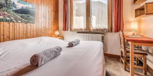 a bedroom with a bed with two rolled towels on it at Chalet Les Lauzes - Chalets pour 10 Personnes MAE-3288 in Champagny-en-Vanoise