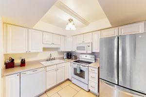 a kitchen with white cabinets and a stainless steel refrigerator at Regency Towers W 707 in Pensacola Beach