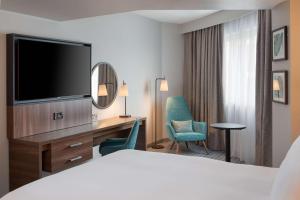 um quarto de hotel com uma cama e uma secretária com uma televisão em DoubleTree by Hilton London Chelsea em Londres
