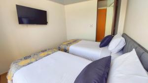 two beds in a hotel room with a tv on the wall at COCOA APARTMENTS in Cota