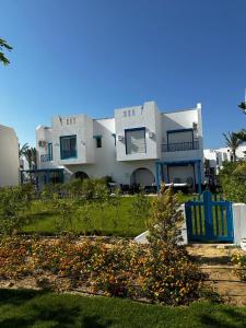 uma grande casa branca com uma cadeira azul em frente em Twin house 4 master Bedrooms premium mountain view Ras Elhekma em Ras Elhekma
