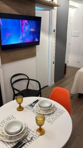 uma mesa branca com cadeiras e uma televisão na parede em Studio São Paulo prox- PUC Allianz Park Esp Unimed 409WBE em São Paulo