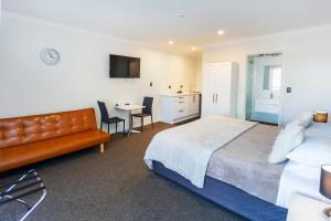 a bedroom with a bed and a table with chairs at Superior Dunedin Apartments in Dunedin