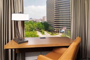 einen Schreibtisch mit einer Lampe, einem Stuhl und einem Fenster in der Unterkunft DoubleTree by Hilton Tulsa at Warren Place in Tulsa