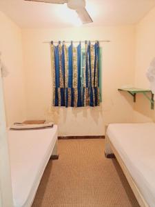 a bathroom with two beds and a window with curtains at Auberge Mariama BA in Gorée