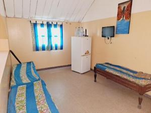 a room with a refrigerator and a bed in it at Auberge Mariama BA in Gorée