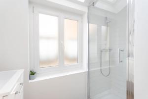 La salle de bains blanche est pourvue d'une douche et d'une fenêtre. dans l'établissement Lille - Bel Appartement Cosy et Lumineux, à Lille