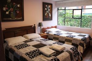 2 camas en una habitación con ventana en Casa de Tulia, en Quito