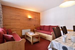 ein Wohnzimmer mit einem roten Sofa und einem Tisch in der Unterkunft Résidence Carroley B - 2 Pièces pour 5 Personnes 97 in Mâcot La Plagne
