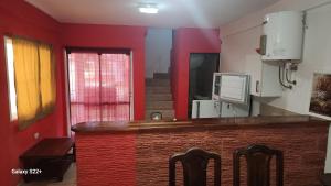 a kitchen with red walls and a counter with chairs at Cabañas La Dorita in Paso de la Patria