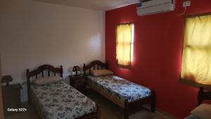 two beds in a room with red walls and a window at Cabañas La Dorita in Paso de la Patria