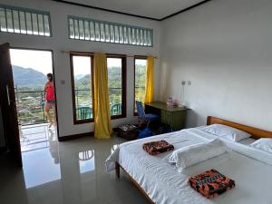Un dormitorio con una cama, un escritorio y ventanas. en FARILA LODGE, en Kelimutu