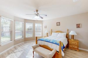 a bedroom with a bed and a chair and windows at Hidden Springs Oasis in San Antonio