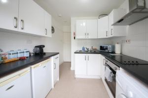 Una cocina con gabinetes blancos y encimeras negras. en Thornton House Apartments, Cambridge - FREE On-site Parking, en Girton 21 fotos más