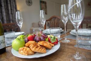 a plate of fruit and pastries on a table with wine glasses at Thornton House Apartments, Cambridge - FREE On-site Parking in Girton