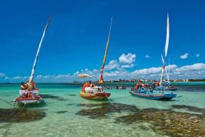 a group of boats in the water on a beach at Duplex Beira Mar Pajuçara Maceió in Maceió
