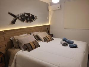 Schlafzimmer mit einem Bett mit weißer Bettwäsche und Kissen in der Unterkunft Apartamento Boutique Barra da Tijuca Península in Rio de Janeiro