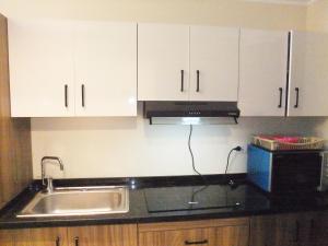 a kitchen with white cabinets and a sink and a microwave at Aldau heights Mathew in Hurghada