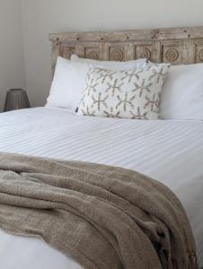 una cama blanca con una manta y almohadas en Araluen Motor Lodge, en Batemans Bay